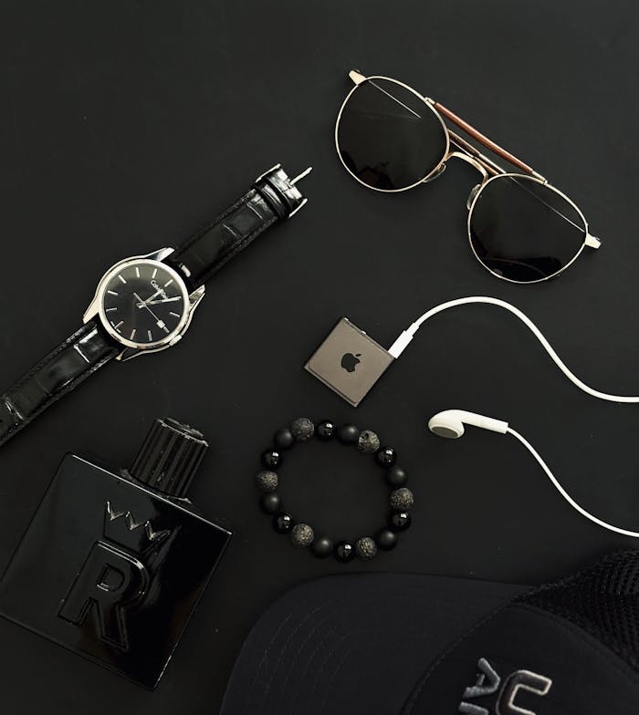 Flat lay of men's fashion accessories including watch, sunglasses, and perfume.
